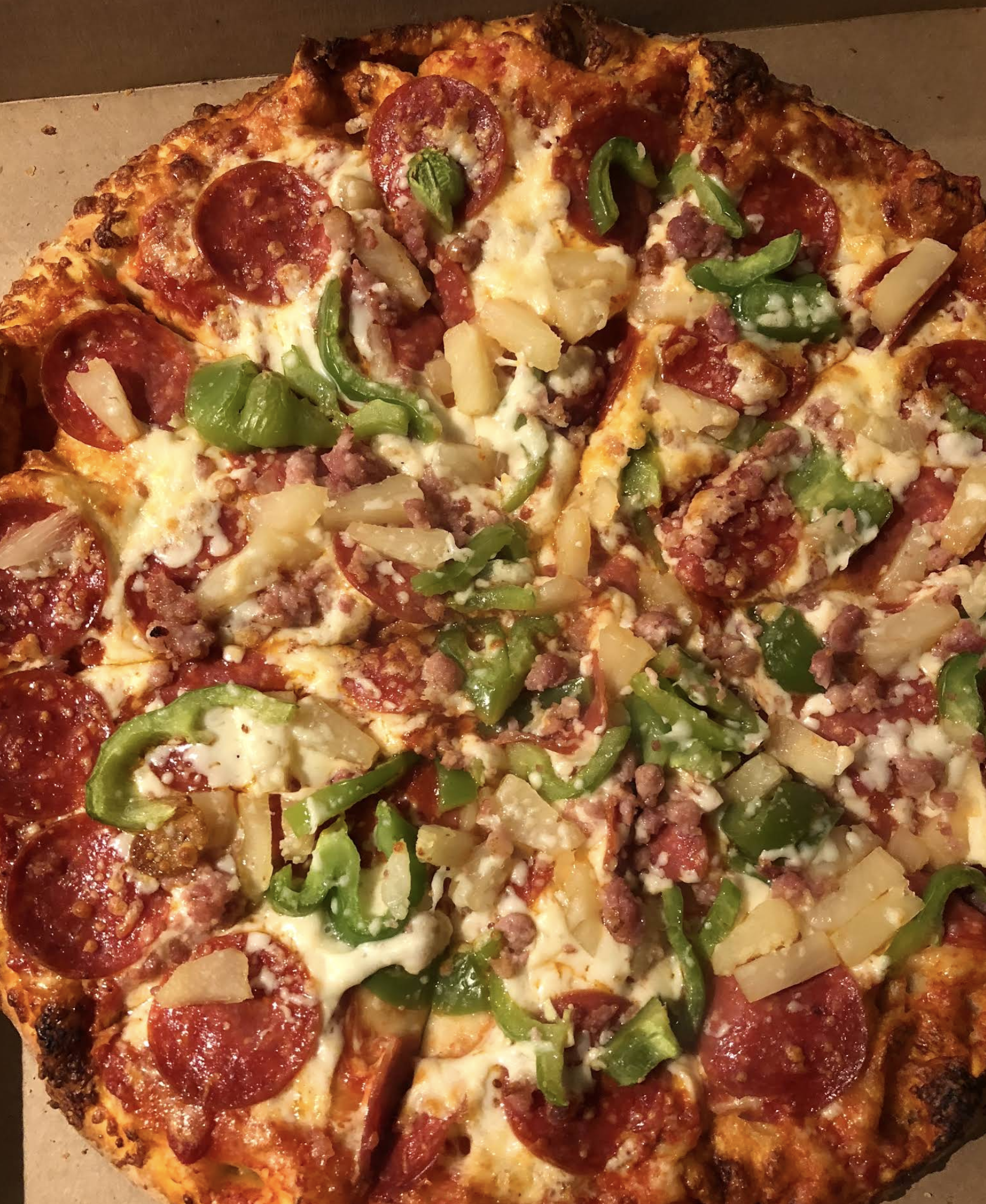 A hearty pizza loaded with pepperoni, sausage, pineapple and green peppers.