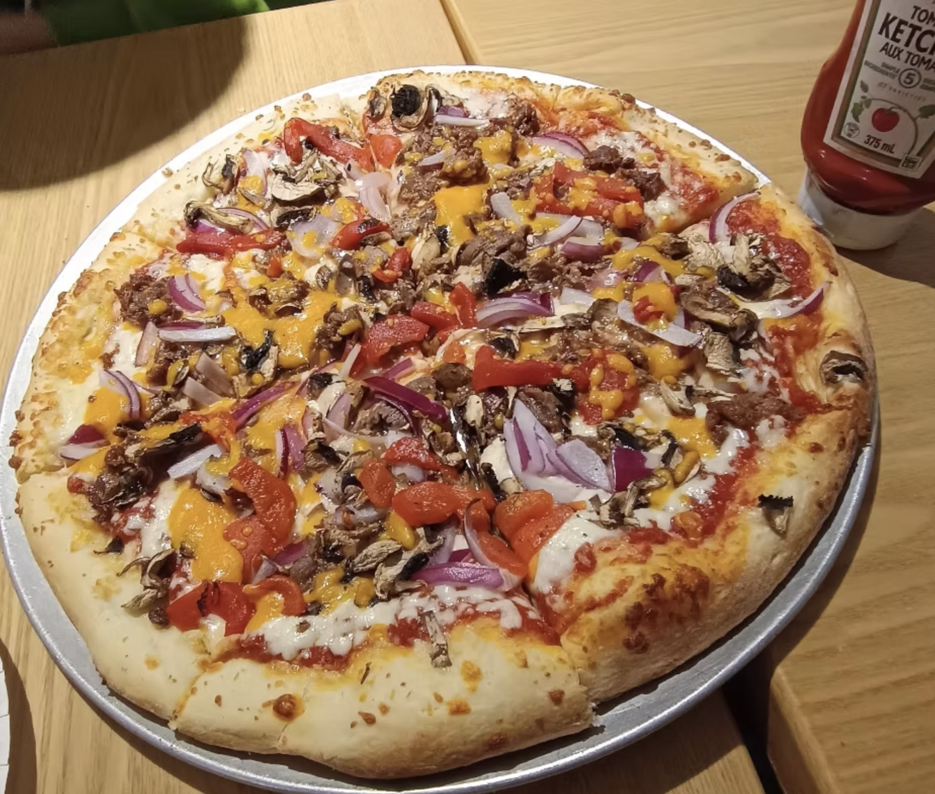 A loaded pizza topped with steak, mushrooms, peppers, onions and plenty of melted cheese.