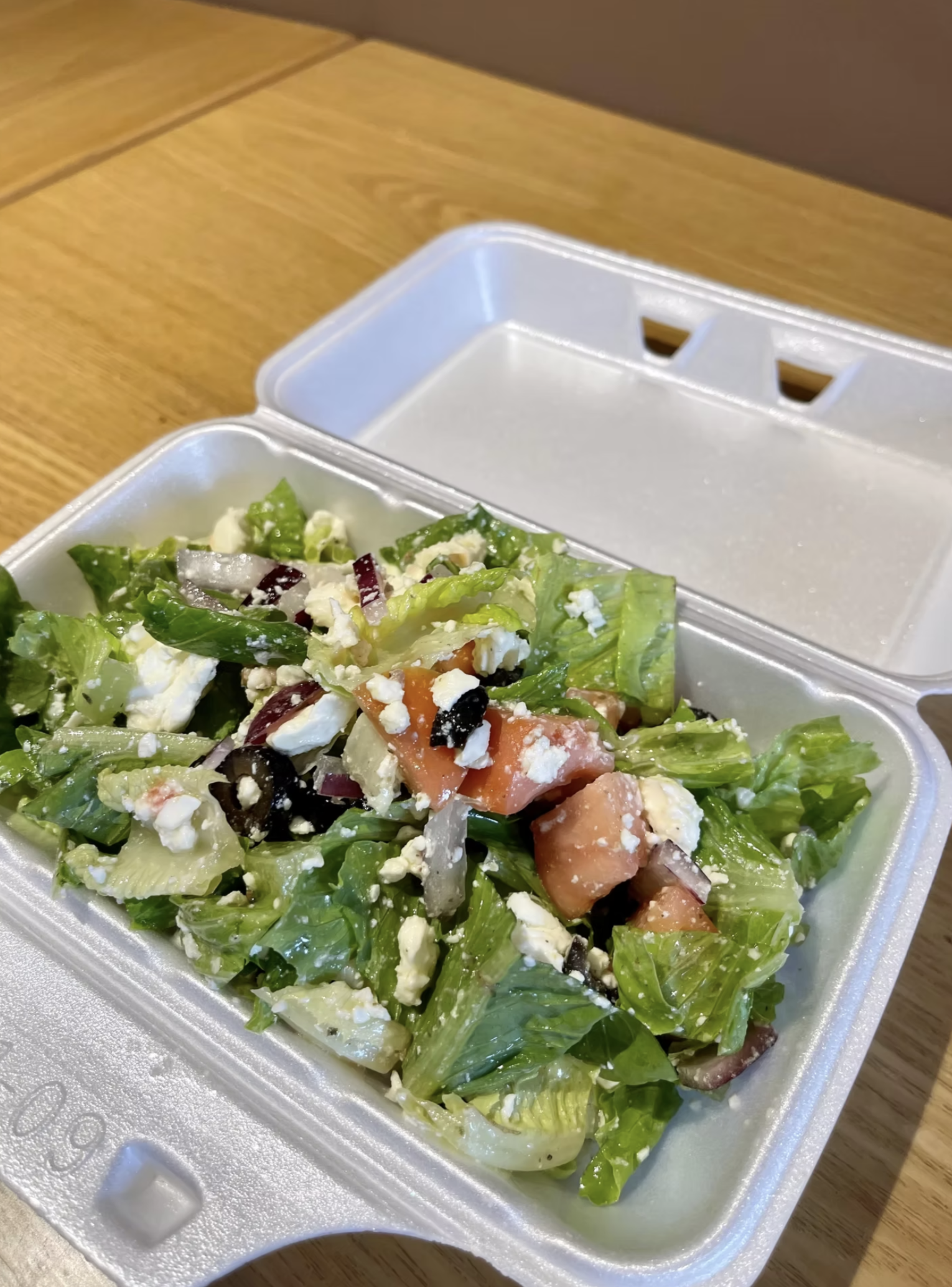 A fresh Greek-style salad with crisp lettuce, tomatoes, onions, olives and feta cheese.